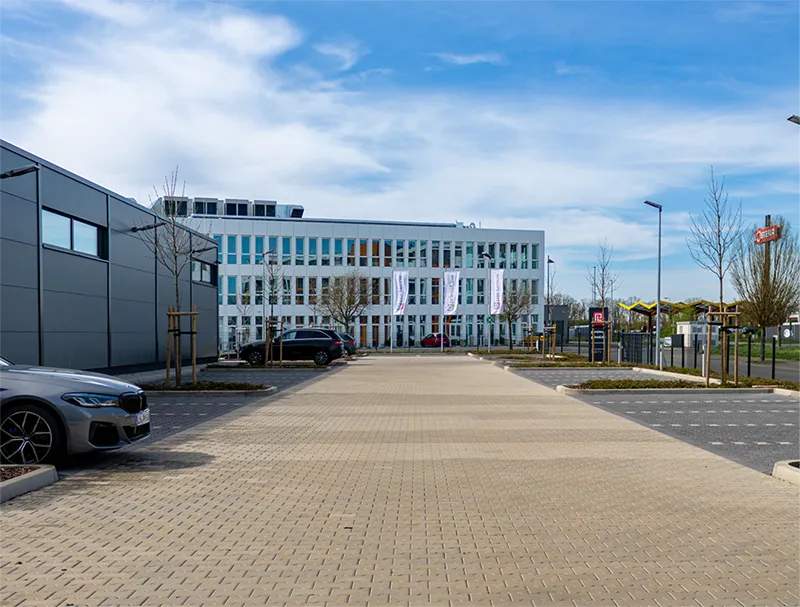 Aufnahme vom eingezäunten Parkplatz mit Rolltor vor dem partimus Gebäude.