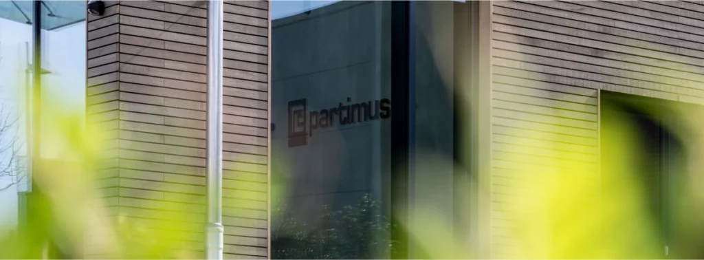 Partimus Logo mit Schriftzug den man durch das Fenster vom Bürogebäude sehen kann.